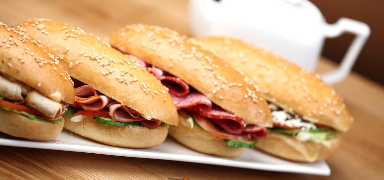 Fresh sandwiches on sesame rolls arranged on a white platter at a cozy bakery café in Moab, Utah.